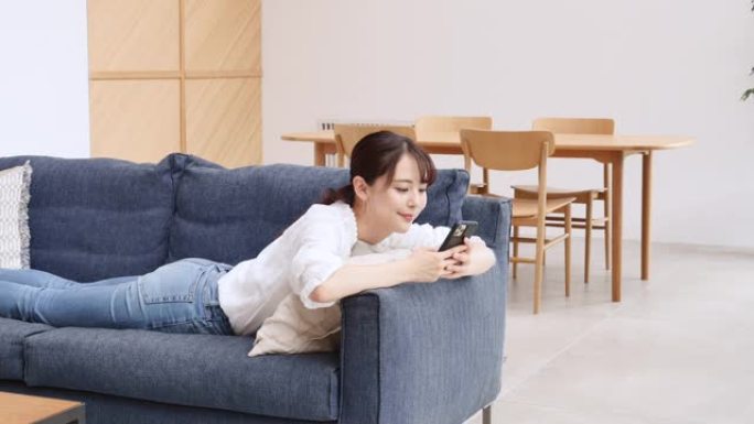 亚洲妇女在沙发上使用智能手机