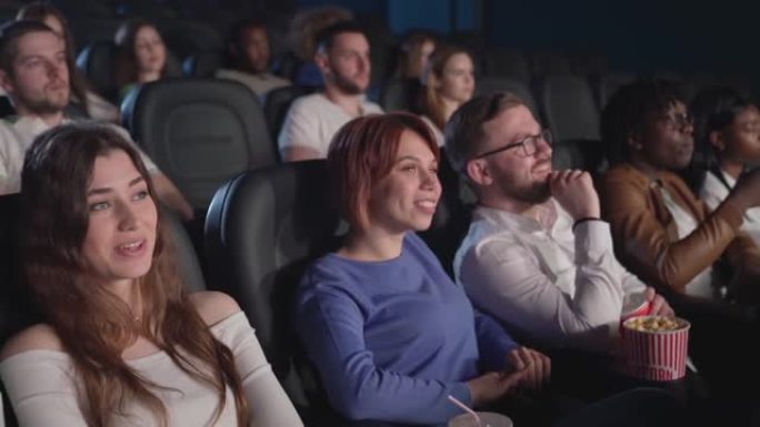 在电影院看喜剧的年轻夫妇。