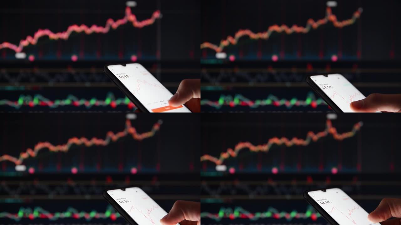 在大屏幕市场价格前的智能手机上检查股票价格的人。在智能手机上查看股票价格的人，在后台的屏幕上查看市场