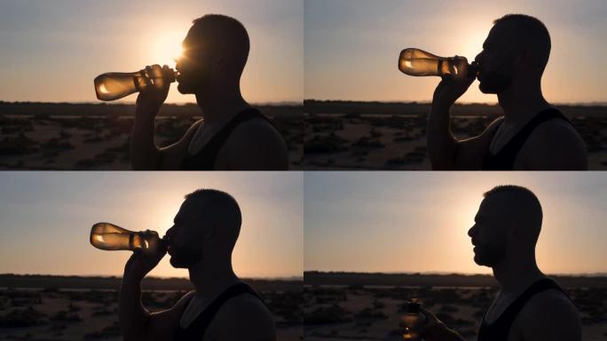 年轻的运动型男子在沙漠中锻炼后喝水