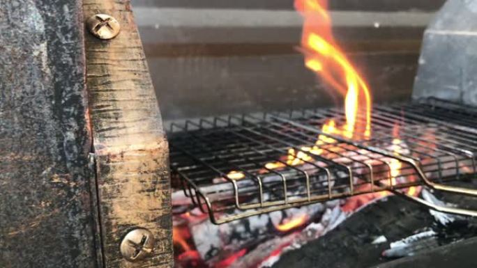篝火在带有烧肉烧烤架的大型家庭烧烤架上燃烧