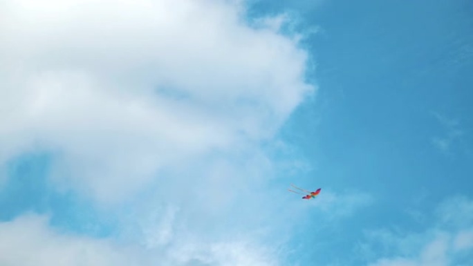 风筝在天空中在云间飞舞。概念。仰视夏天的蓝天白云和飞扬的彩虹彩色风筝，自由和童年的概念。