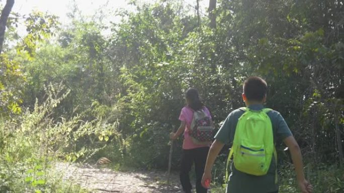 背包客的孩子们早晨带着阳光一起走进森林到山峰，积极的生活方式理念。
