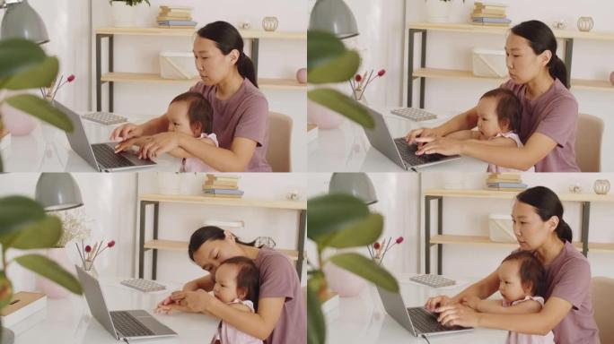 亚洲母亲在家休育儿假在笔记本电脑上工作