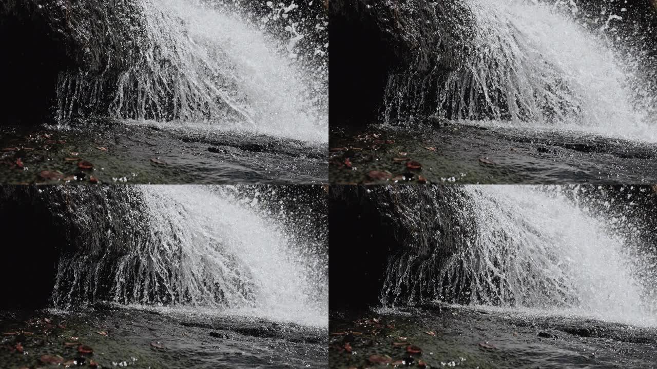 山瀑布，水倾泻在岩石上，瀑布溅落在石头上。