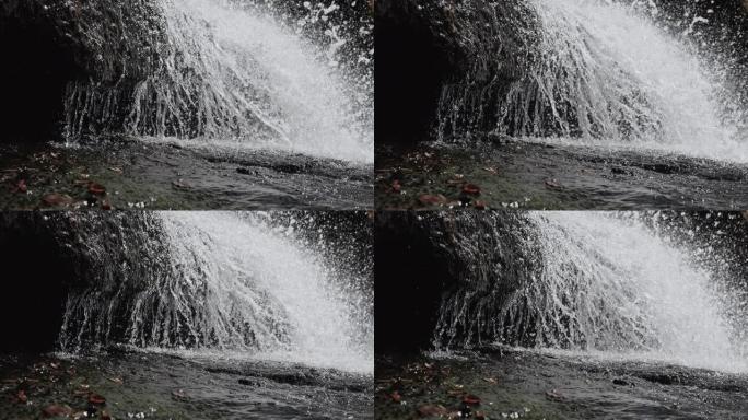 山瀑布，水倾泻在岩石上，瀑布溅落在石头上。