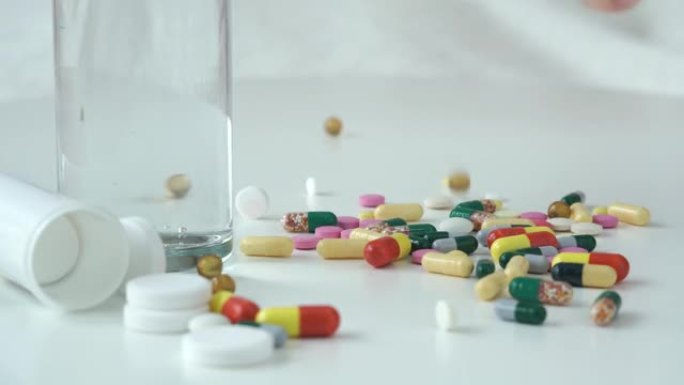 彩色药丸从医疗罐中掉落，散落在水玻璃背景上的桌子上。药丸和毒品。医学概念。