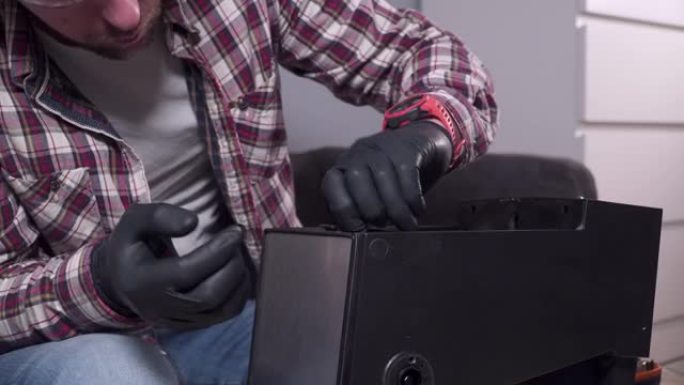 一个年轻人正试图在家里修理自己的厨房电器，咖啡机。高加索男性用穿着格子衬衫、安全眼镜和手套的螺丝刀修