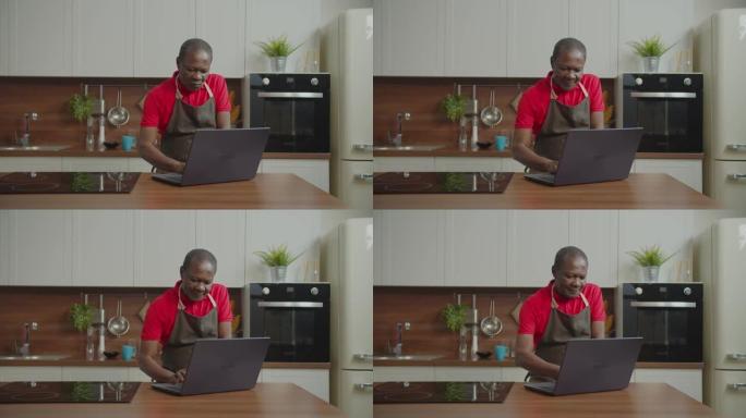 退休的非洲男性网络在厨房的笔记本电脑上