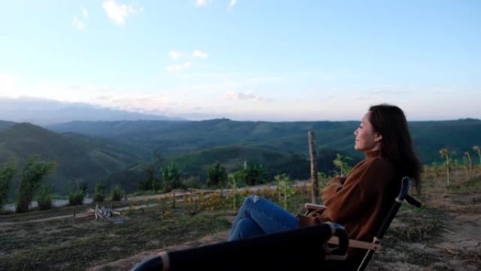 女性旅行者的慢动作早上坐在山顶上看日出