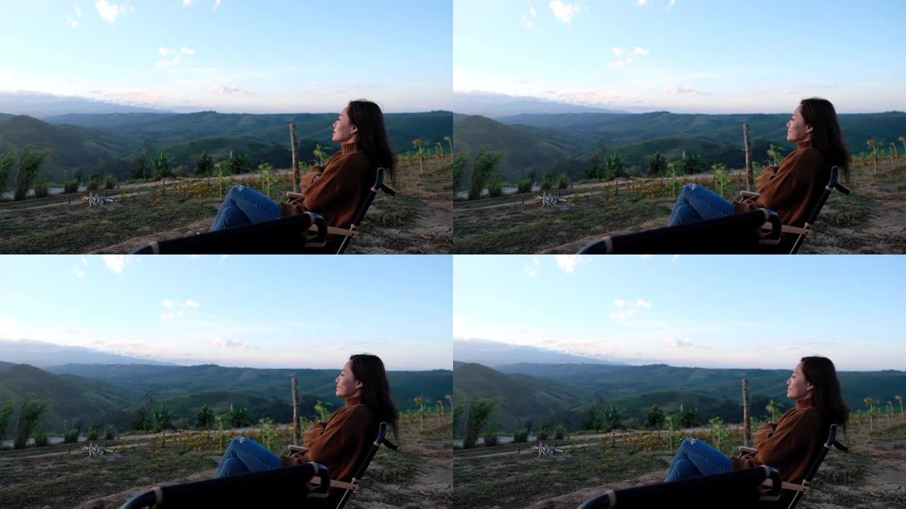 女性旅行者的慢动作早上坐在山顶上看日出