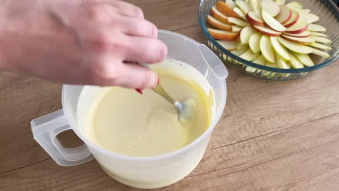 为馅饼准备面团的过程。女人用勺子搅拌面团做苹果派。烹饪概念。