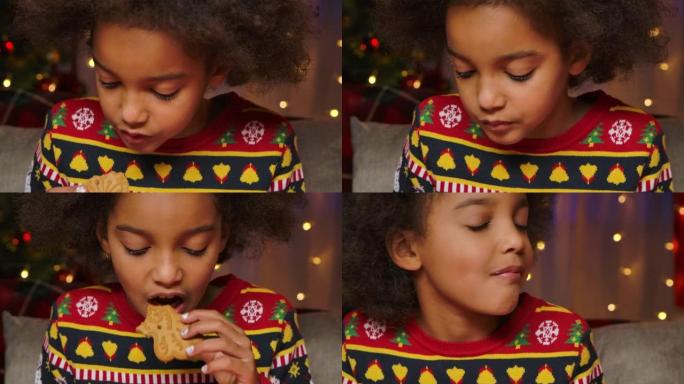 可爱的非洲裔美国女孩正在享受传统的圣诞饼干。一个穿着带有节日装饰的厨房背景上印有新年字样的毛衣的孩子