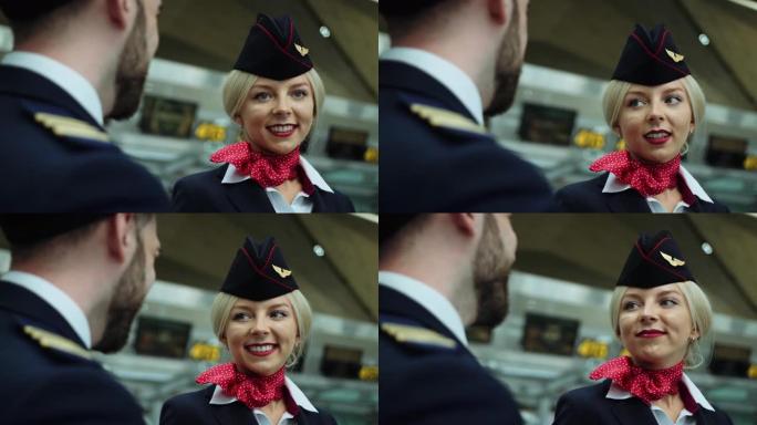 在机场空姐，金发和蔼地微笑着，与飞行员交谈。欧洲妇女穿着深蓝色制服，在她的白衬衫上系着猩红色的围巾。
