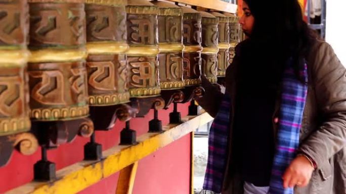 女孩旋转佛教寺院祈祷轮与手特写夹