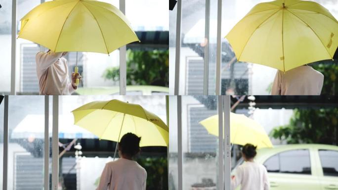 亚洲女孩在雨天在房子前使用黄色雨伞，生活方式概念。