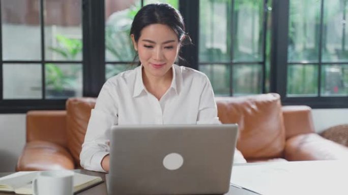 亚洲年轻女性在家工作时使用笔记本电脑、耳机与办公室同事在线会面。女孩避免社交距离密切接触者人保护，防