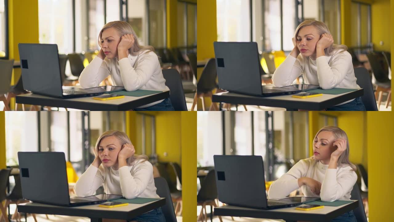 年轻的白人妇女无聊地在办公室的电脑和平板电脑上工作，筋疲力尽，没有动力。专注于家庭办公室的女学生远程