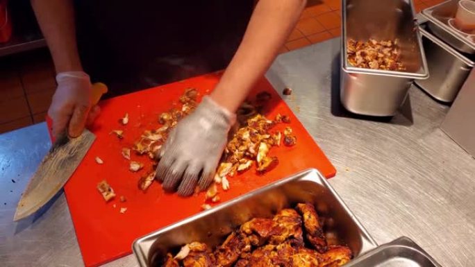 墨西哥快餐店的一个人戴着防护手套用刀切肉和鸡肉