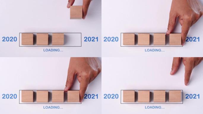 用手将木方块放入进度条中，加载快乐的新2020年2021年。新年快乐概念。
