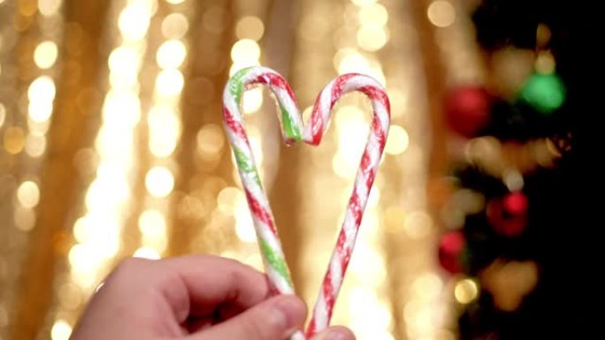 手握心形糖果棒，圣诞灯背景。