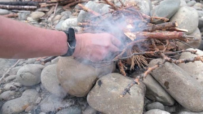 一个人在特殊火柴的帮助下在石头上生火。一个男人的手点燃火的特写镜头。