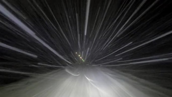 在冬天的夜晚，在下雪的路上开车。大雪反射着汽车前灯的光。