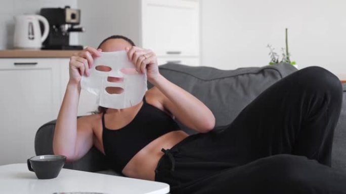 年轻的千禧一代妇女在家在脸上涂布面具。健康放松时间