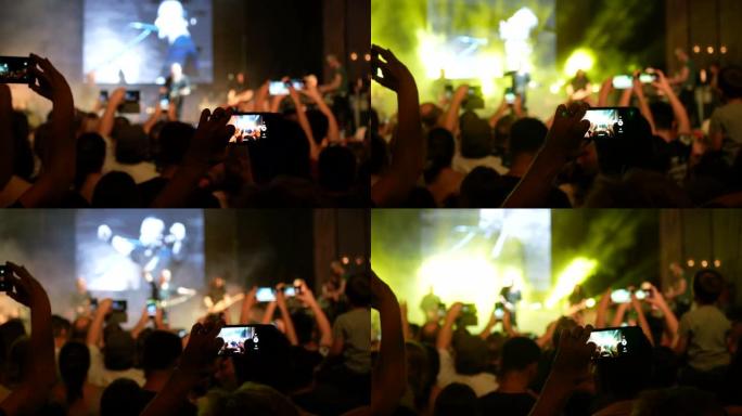 欣赏音乐家乐队现场音乐会的人们的剪影在明亮的聚光灯下在舞台上表演歌曲