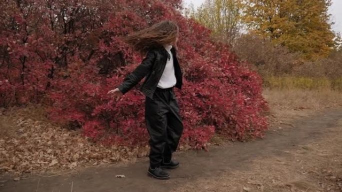 穿着皮夹克和皮裤的小女孩在秋天的公园里旋转