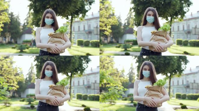 戴着防护面具的年轻女子随身携带带有商店产品的袋子。冠状病毒大流行。在检疫运送食物