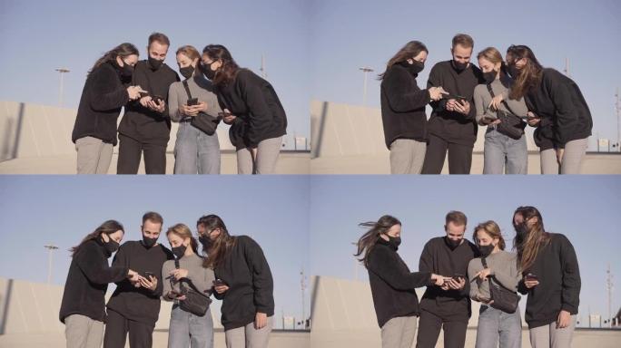 一群戴着口罩的朋友使用智能手机。他在手机上教他们一些有趣的东西。新型冠状病毒肺炎季节新的正常生活方式