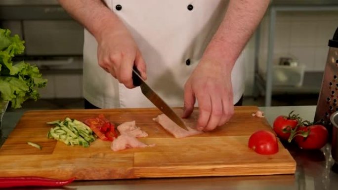 厨师在切菜板上切鸡肉和蔬菜的特写镜头。