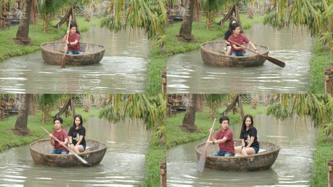 年轻的亚洲夫妇正在运河中划船。