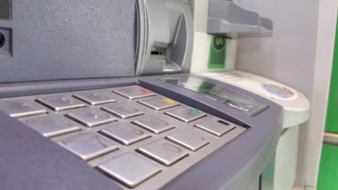 一个人在本地银行的atm机上使用借记卡提款，同时在机器键盘上键入pin码