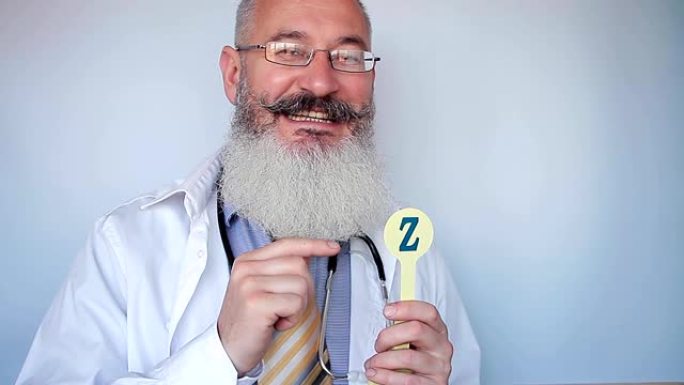 成熟的大胡子言语治疗师显示字母Z，并解释如何正确发音。好医生。灰色背景。