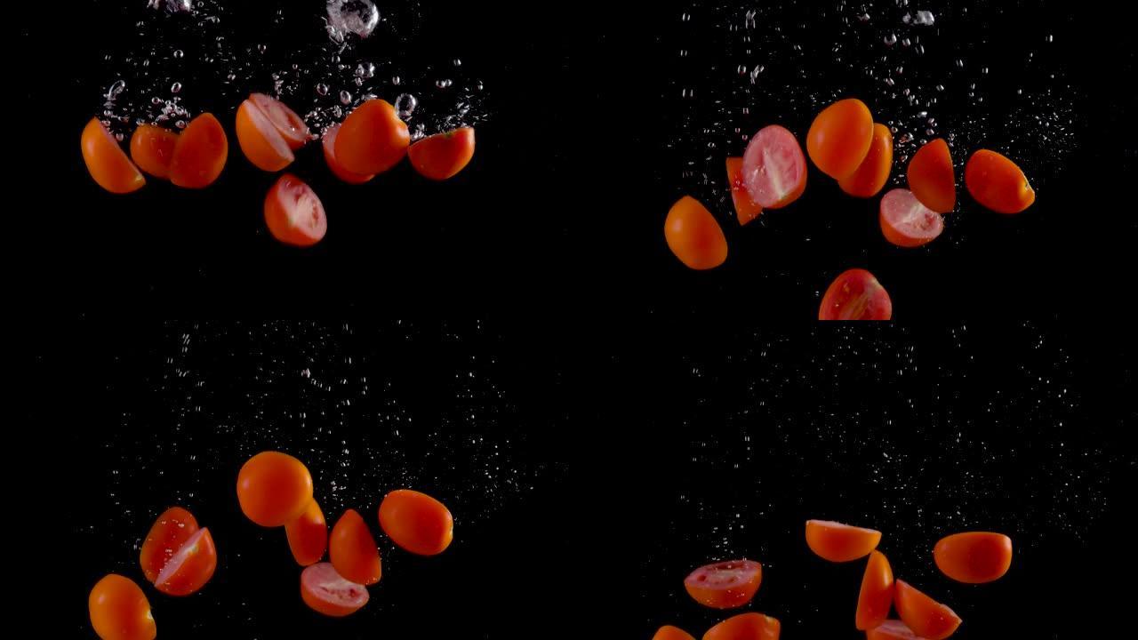 樱桃番茄落入黑色背景的水中。慢动作