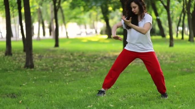 一个女人在公园里做太极拳气功。东方武术武术