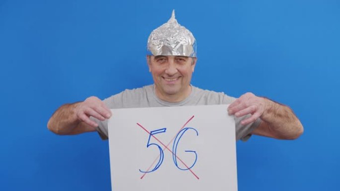老人拿着没有5g标志的标语牌。站在蓝色背景下抗议5g技术和5g兼容天线部署。