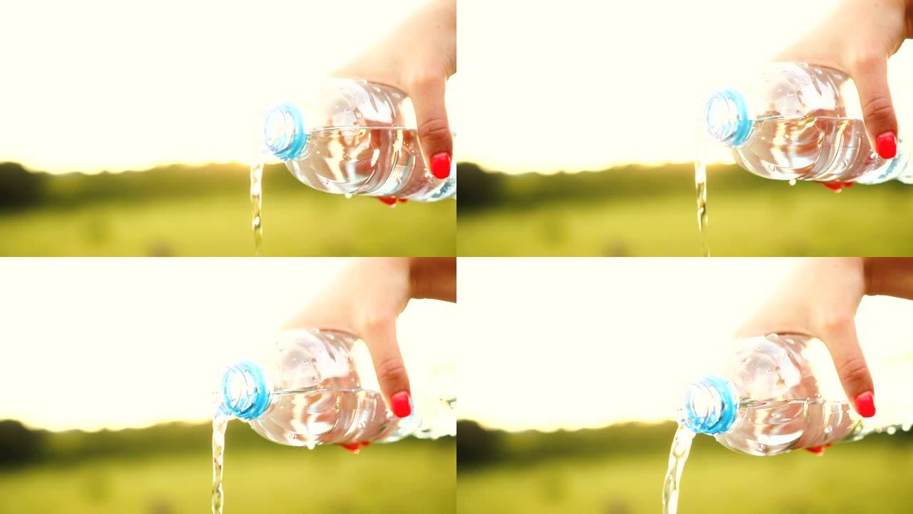 女性手在公园用塑料瓶倒水