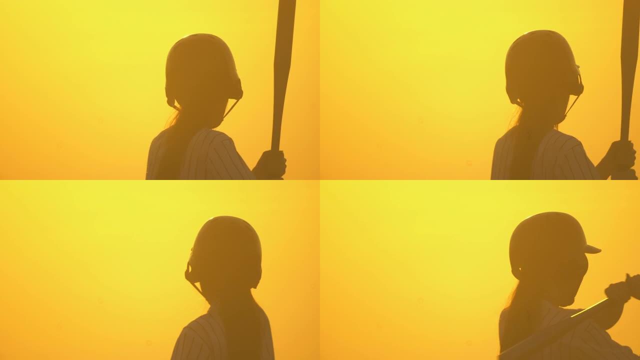 一个戴着棒球手套的女孩在日落时打棒球