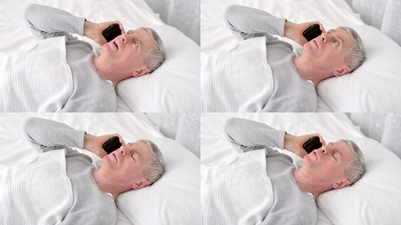 积极的老人在床上用智能手机聊天