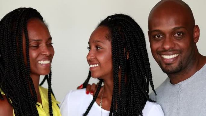 美丽的非洲黑人家庭对着镜头微笑。混合种族的父亲，母亲和十几岁的女儿