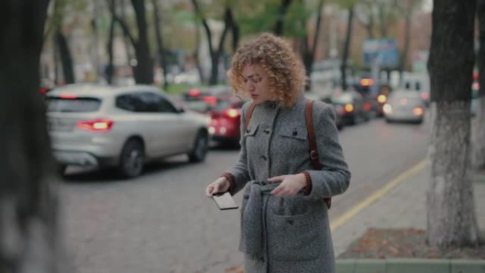 女人在等出租车，当时看着智能手机