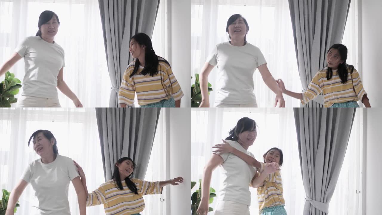 快乐的亚洲单身母亲和女儿一起在家里的窗户附近跳舞，积极的生活方式理念。