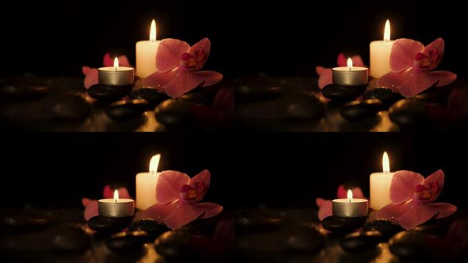 深色背景上有水疗石和兰花的蜡烛。芳香疗法、美容和健康理念