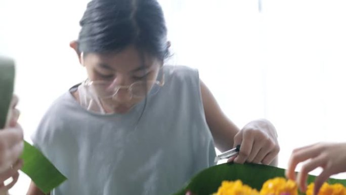 快乐的亚洲女孩为kathong插花 (用香蕉叶和花朵制成，漂浮在河中祈祷和感谢) 一起在家，为夜晚做