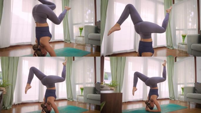 年轻女子在家练习倒立瑜伽姿势。亚洲女孩在室内倒立时在客厅锻炼和伸展