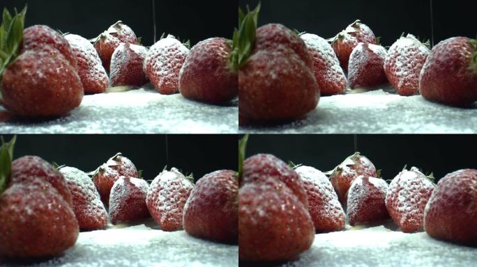 用糖粉倒草莓的水。草莓特写。黑色背景草莓的宏观拍摄。