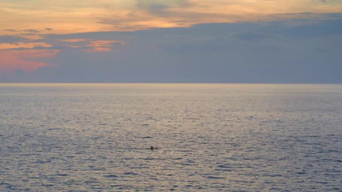日落时分乌云和黄色天空的小浪在海上皮划艇人的剪影